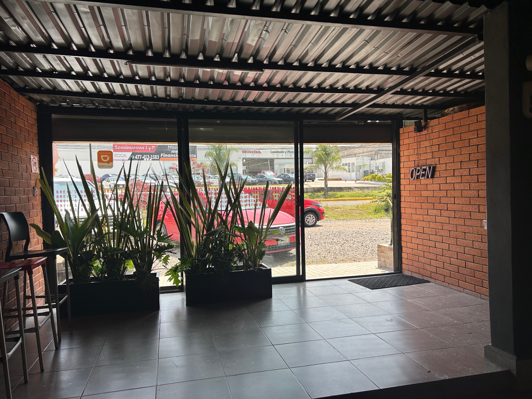 Entrada de Breik's con plantas y ventanal hacia la calle